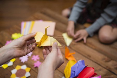 Photo for Parent and child hands playing with origami - Royalty Free Image