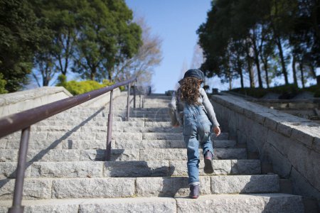 Photo for Little girl climbing stairs in daytime - Royalty Free Image