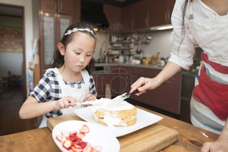 Téléchargez les photos : Petite fille et mère faire du gâteau à la maison - en image libre de droit