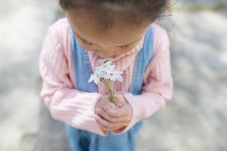 Téléchargez les photos : Petite fille avec des fleurs dans la nature - en image libre de droit
