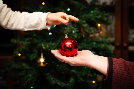 Photo for Grandmother and granddaughter handing over Christmas tree decorations - Royalty Free Image