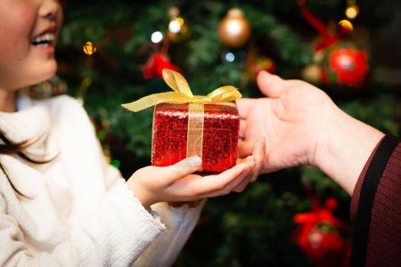 Photo for Grandmother and granddaughter handing over Christmas gift - Royalty Free Image