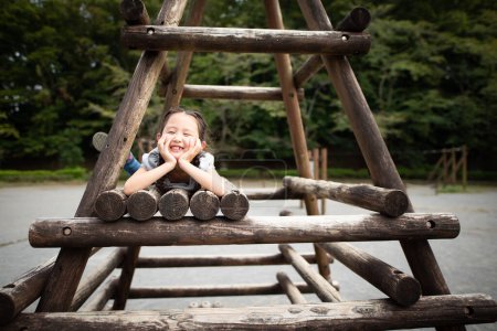 Foto de Lindo poco asiático chica jugando en playground en el parque - Imagen libre de derechos