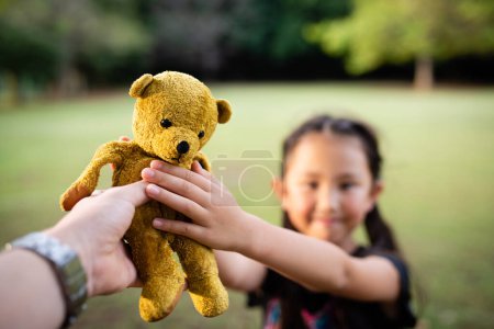 Photo for Parent and child handing teddy bear - Royalty Free Image