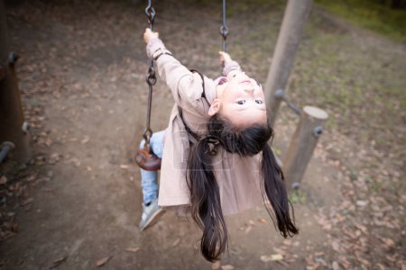 Photo for Cute little asian  girl on swing  on playground  in the park - Royalty Free Image