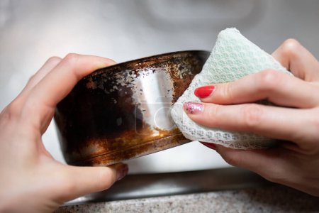 Frauenhände waschen nur die Hälfte einer verbrannten Pfanne