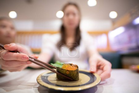 Foto de Mujer comiendo sushi de salmón con palillos - Imagen libre de derechos