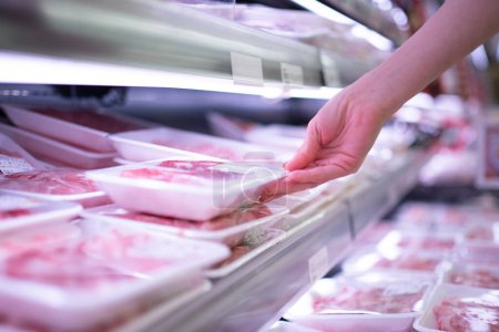 Téléchargez les photos : Main de femme ramassant de la viande emballée à l'épicerie - en image libre de droit