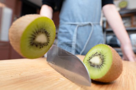 Foto de Mujer cortando una fruta kiwi por la mitad - Imagen libre de derechos