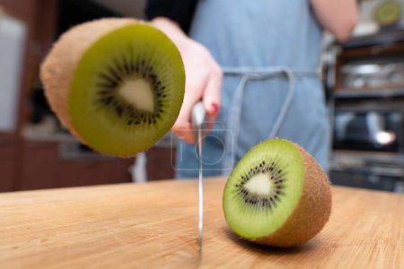 Foto de Mujer cortando una fruta kiwi por la mitad - Imagen libre de derechos