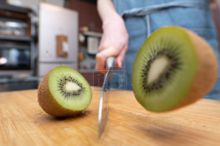 Photo for Woman cutting a kiwi fruit in half - Royalty Free Image