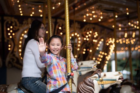 Photo for Mother and daughter riding a merry go round - Royalty Free Image