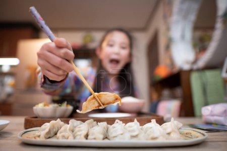 Photo for Girl eating dumplings with chopsticks - Royalty Free Image