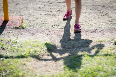 Téléchargez les photos : Les jambes et les ombres d'un enfant jouant une tige de fer - en image libre de droit