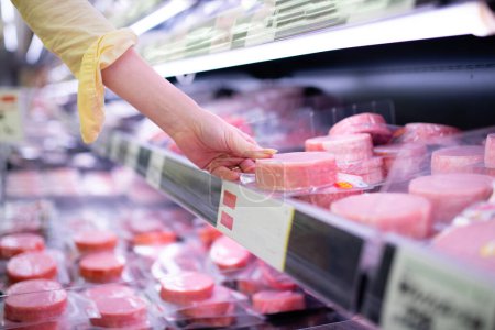 Téléchargez les photos : La main d'une femme ramassant du jambon dans un supermarché - en image libre de droit