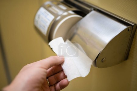 Téléchargez les photos : Main utilisant du papier toilette dans les toilettes - en image libre de droit