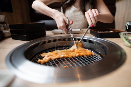 Foto de Una mujer comiendo en un restaurante japonés de yakiniku - Imagen libre de derechos