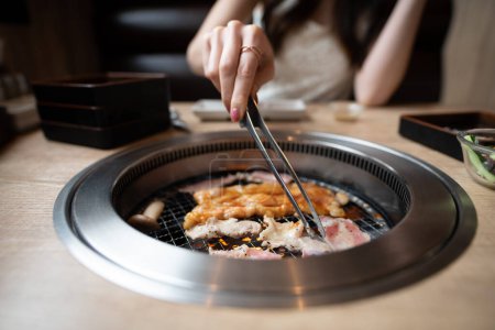 Foto de Una mujer comiendo en un restaurante japonés de yakiniku - Imagen libre de derechos