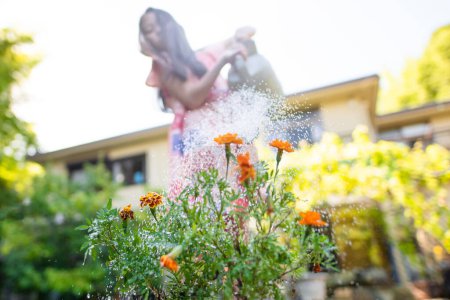 Foto de Una chica que riega flores con una regadera - Imagen libre de derechos