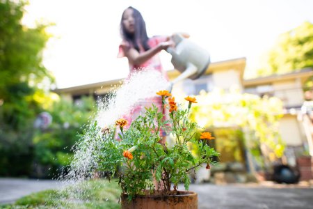Foto de Una chica que riega flores con una regadera - Imagen libre de derechos