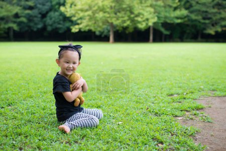 Téléchargez les photos : Little asian girl with teddy bear  in park. - en image libre de droit