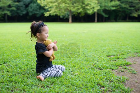 Téléchargez les photos : Little asian girl with teddy bear  in park. - en image libre de droit