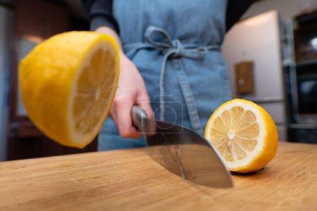Téléchargez les photos : Femme coupant du citron dans la cuisine - en image libre de droit