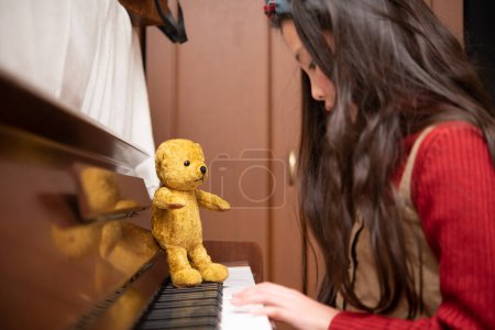 Téléchargez les photos : Ours en peluche apprenant à un enfant à jouer du piano - en image libre de droit