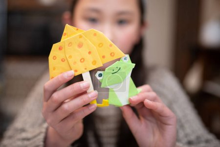 Téléchargez les photos : Une fille avec un origami grenouilles - en image libre de droit