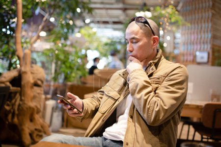 Foto de Hombre mirando teléfono inteligente en la cafetería - Imagen libre de derechos