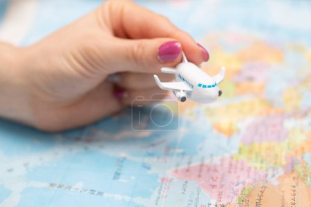 Téléchargez les photos : Main de femme tenant jouet avion et carte du monde - en image libre de droit