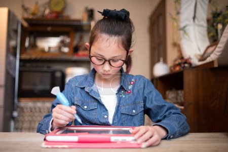 Photo for Girl with glasses learning on tablet at home - Royalty Free Image