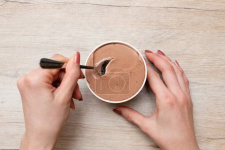 Téléchargez les photos : Mains de femme mangeant de la glace au chocolat - en image libre de droit