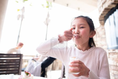 Foto de Una chica comiendo muchos dulces en un restaurante - Imagen libre de derechos
