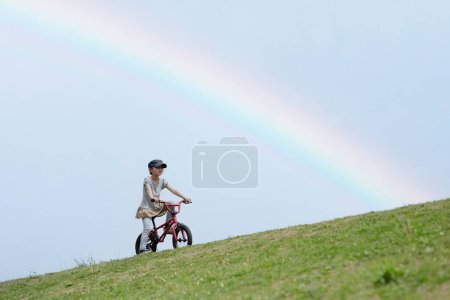 Photo for Girl riding a bicycle in a rainbow meadow - Royalty Free Image