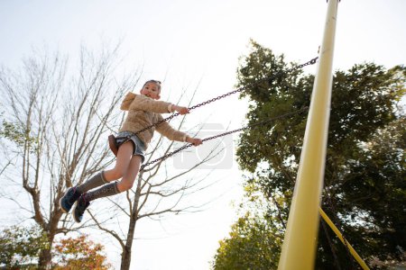 Téléchargez les photos : Fille jouer sur une balançoire dans le parc - en image libre de droit