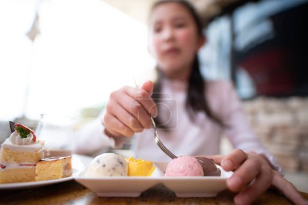 Téléchargez les photos : Une fille qui mange beaucoup de bonbons dans un restaurant - en image libre de droit