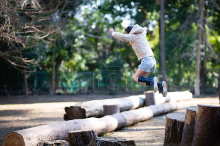 Téléchargez les photos : Un enfant qui saute dans un parc forestier - en image libre de droit