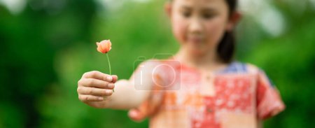 Photo for Girl handing over poppy flower - Royalty Free Image