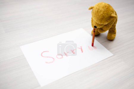 Photo for Teddy bear writing 'sorry' on paper - Royalty Free Image