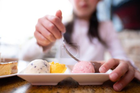 Téléchargez les photos : Une fille qui mange beaucoup de bonbons dans un restaurant - en image libre de droit