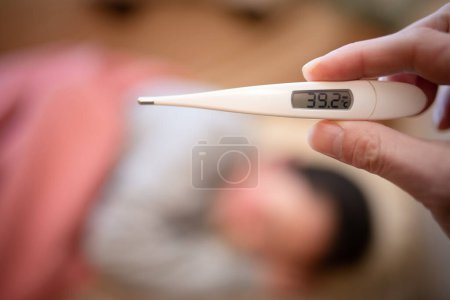 Téléchargez les photos : Un enfant malade, une mère inquiète, et une main avec un thermomètre - en image libre de droit