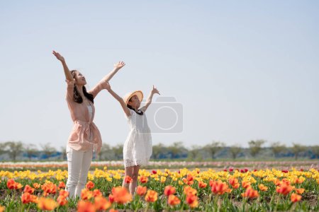 Foto de Madre e hija abren brazos en jardín de flores - Imagen libre de derechos