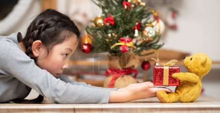 Photo for Girl receiving a Christmas gift from a teddy bear - Royalty Free Image
