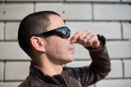 Foto de Hombre con gafas de sol cerca de la pared de ladrillo - Imagen libre de derechos