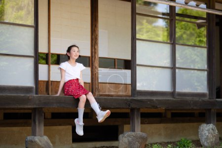 Téléchargez les photos : Une fille se relaxant sur le porche d'une maison japonaise - en image libre de droit