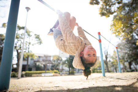 Foto de Chica jugando en la barra horizontal en el parque - Imagen libre de derechos