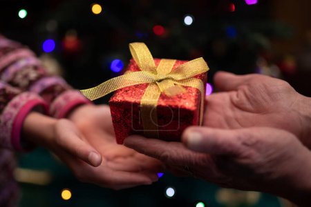 Photo for Hands of grandmother and granddaughter handing a christmas present - Royalty Free Image