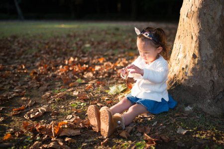 Téléchargez les photos : Fille jouer avec les feuilles tombées - en image libre de droit