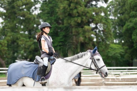 Téléchargez les photos : Fille pratiquant l'équitation un jour de pluie - en image libre de droit